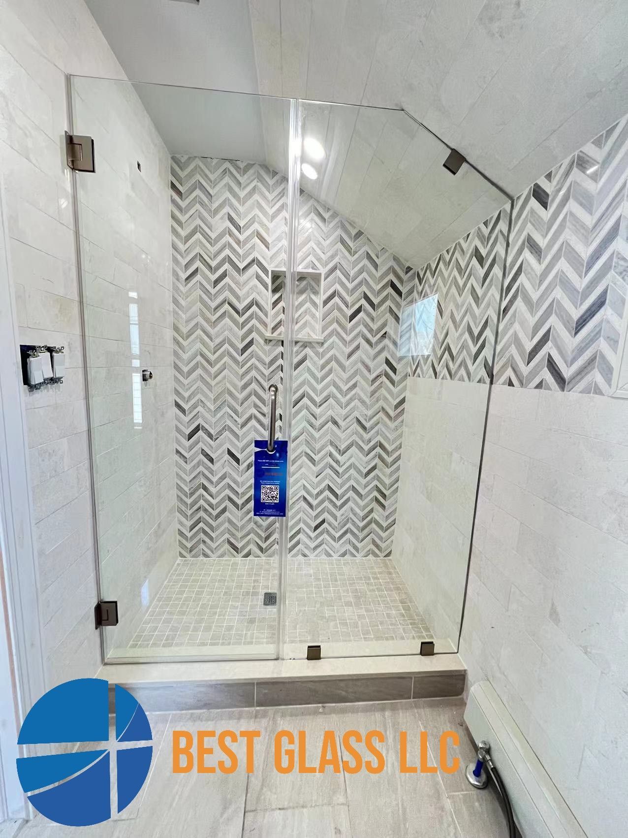 A bathroom with a walk in shower with a herringbone pattern on the wall.