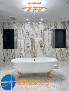 A bathroom with a bathtub and a marble wall.