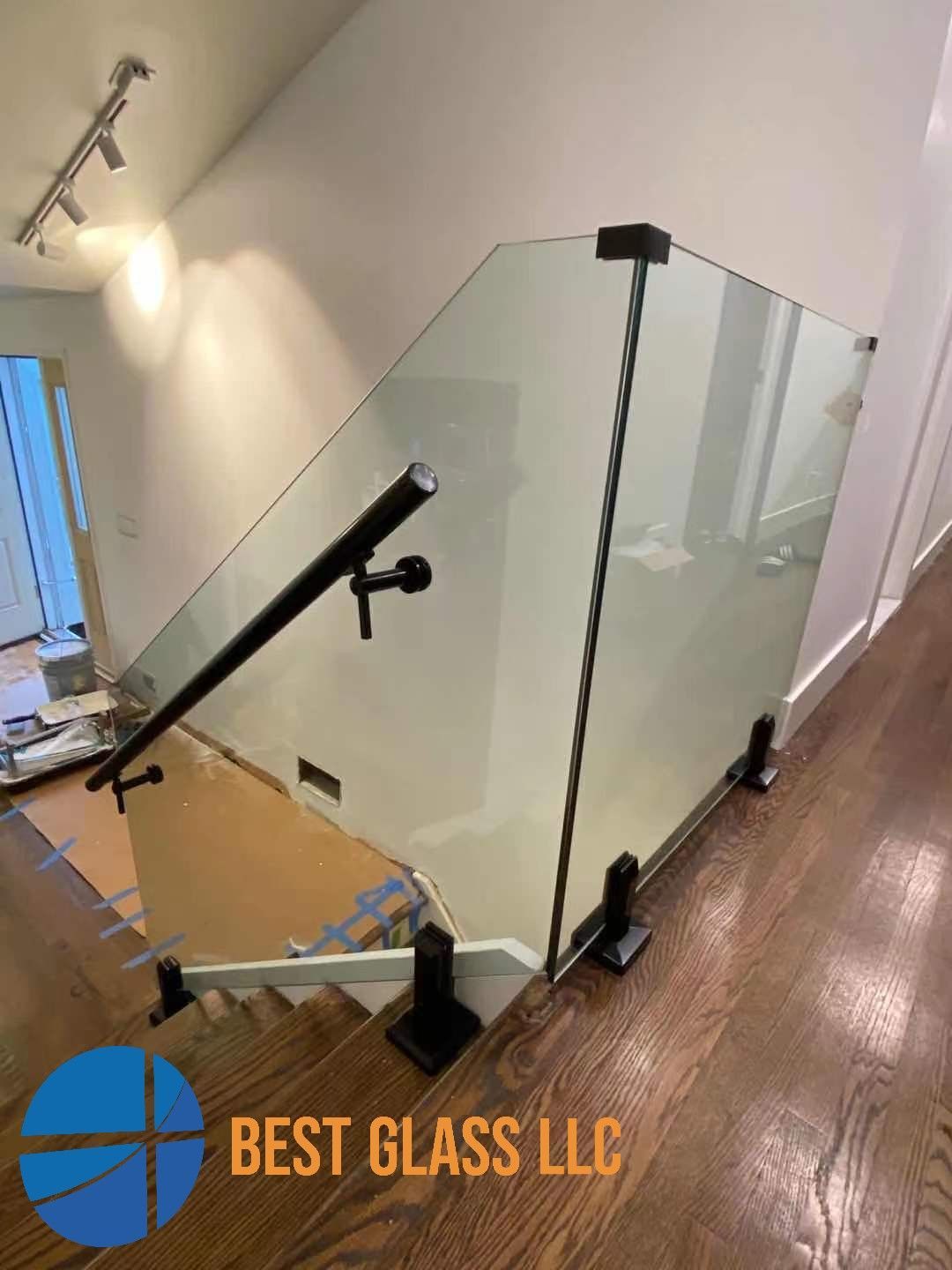 A staircase with a glass railing and a black railing.