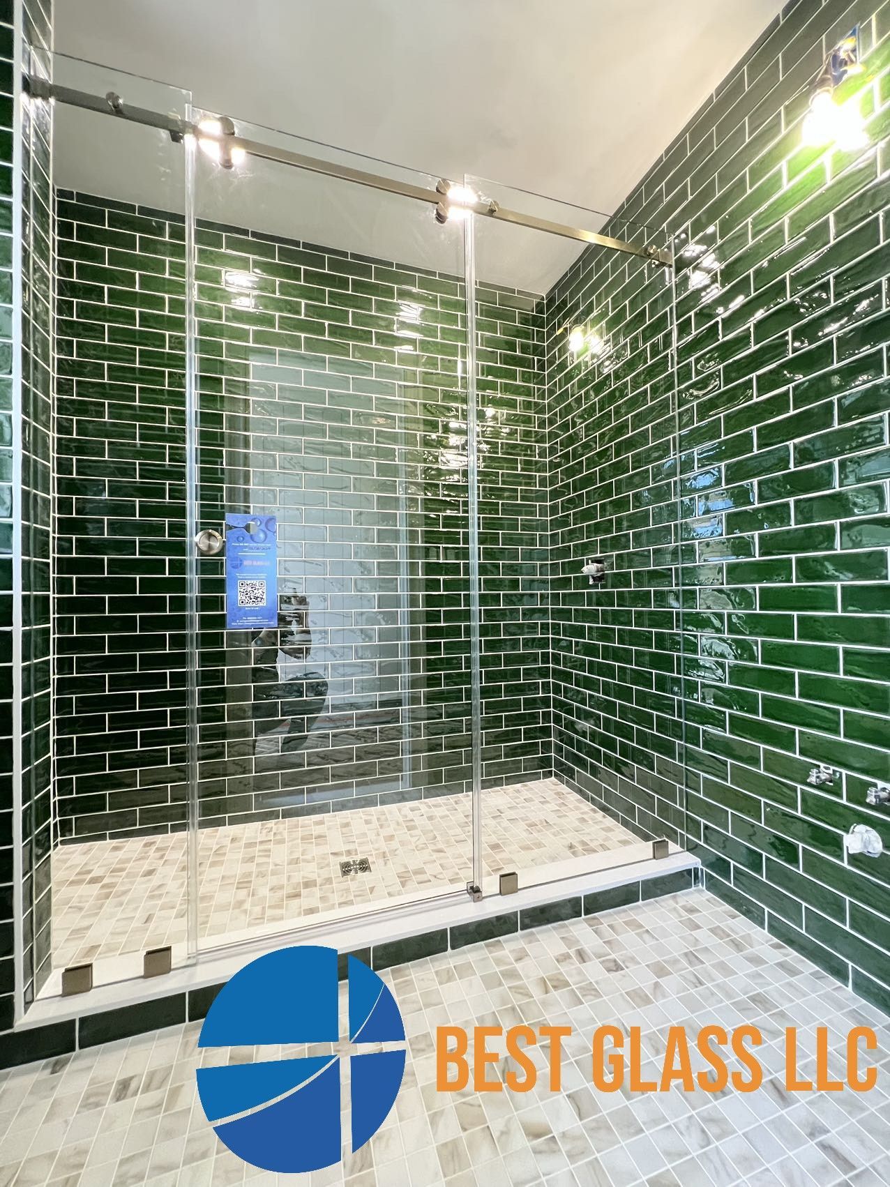 A bathroom with green tiles and a sliding glass shower door.
