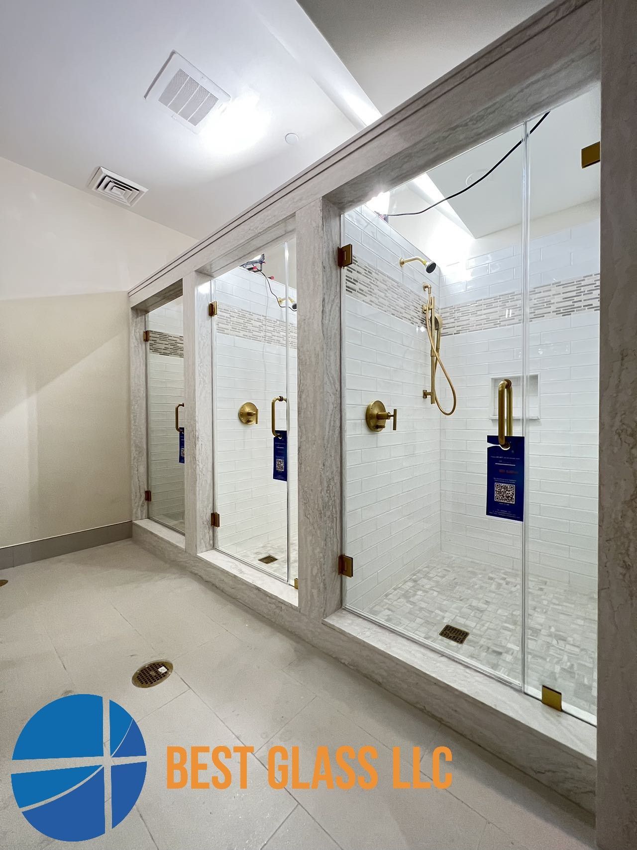 A bathroom with a row of shower stalls and a sign that says best glass llc