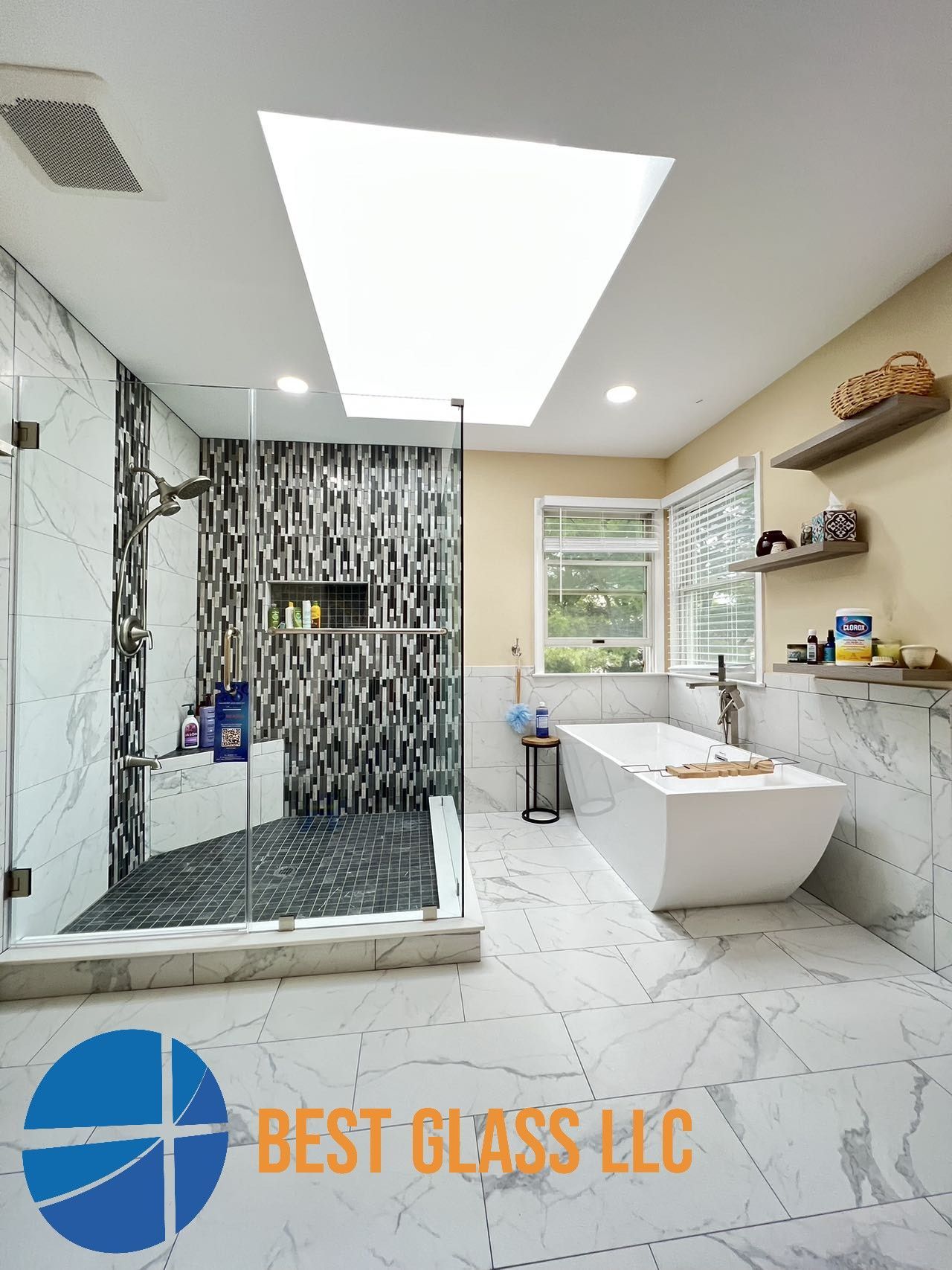 A bathroom with a bathtub and a shower with a skylight from best glass llc