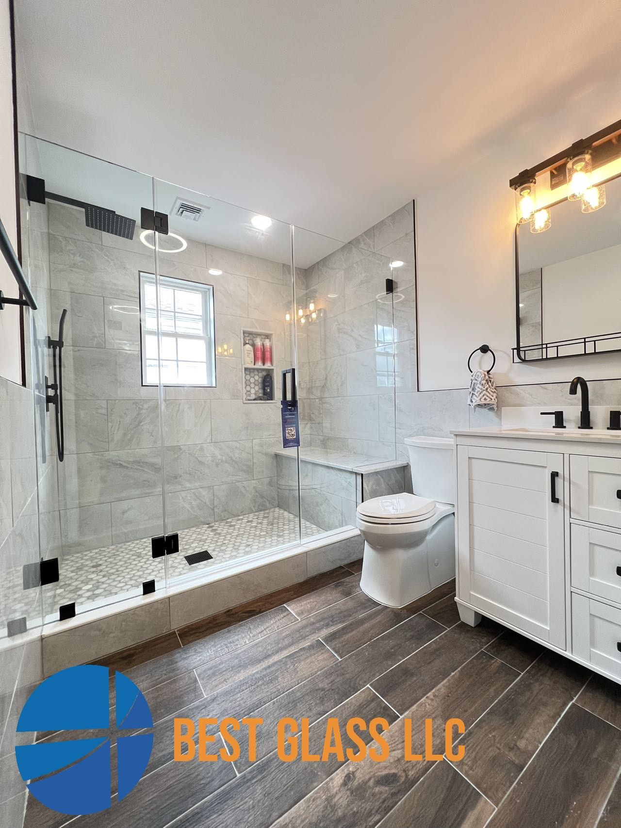 A bathroom with a walk in shower , toilet , sink and mirror.