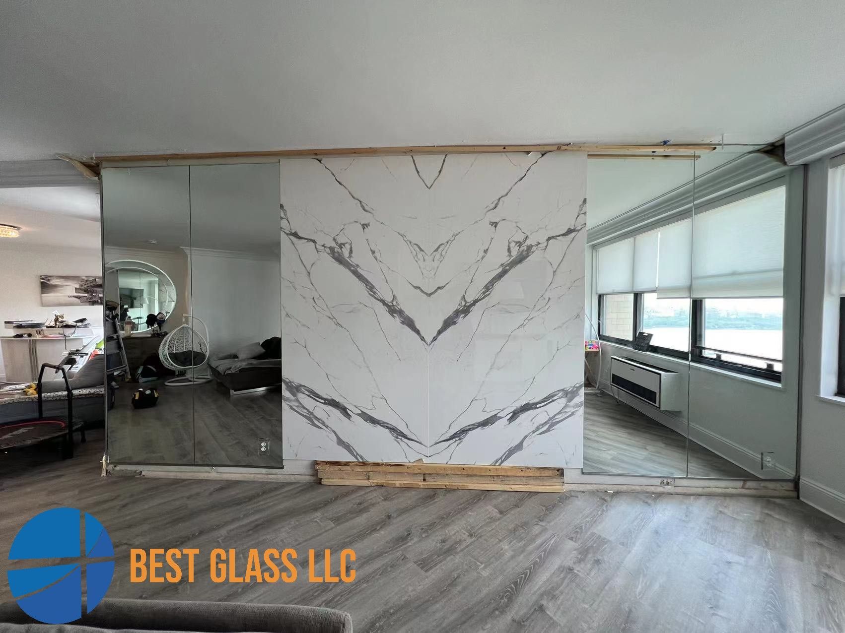 A living room with a large mirror and a marble wall.