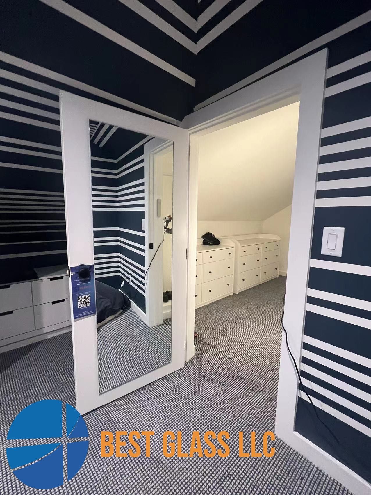A room with striped walls and a mirror on the door