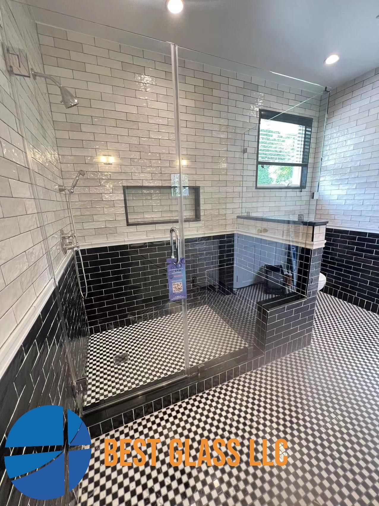 A bathroom with black and white tiles and a walk in shower.