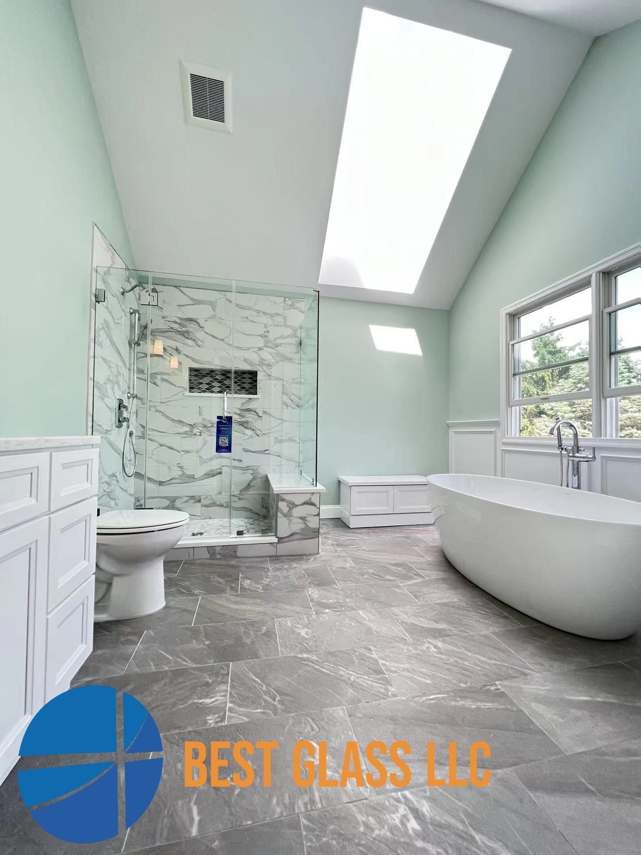 A bathroom with a tub , toilet , shower and skylight.