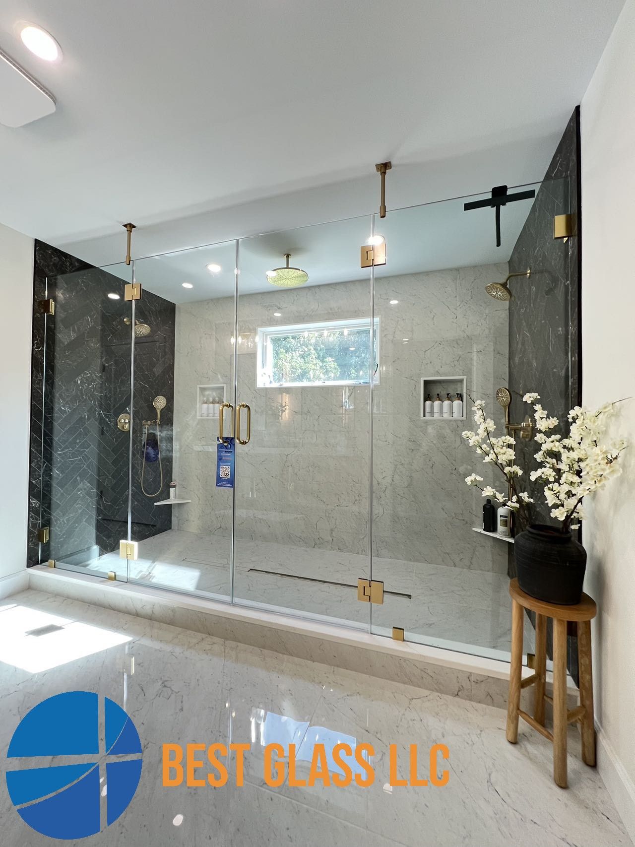 A bathroom with a walk in shower and a sign that says best glass llc