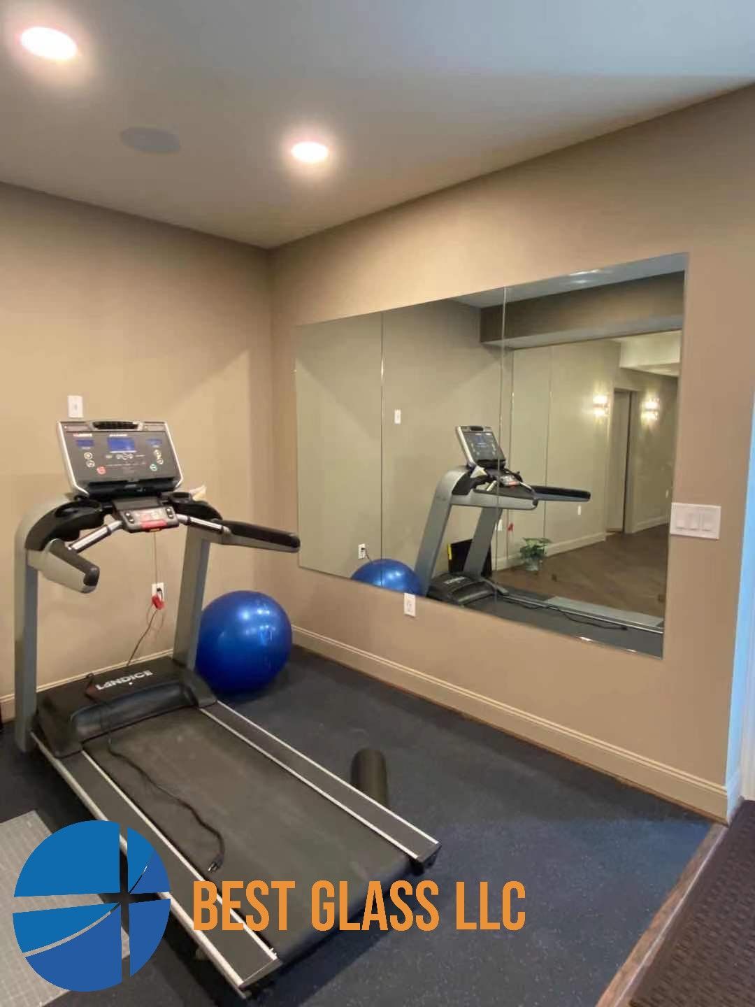 A treadmill is sitting in front of a large mirror in a gym.