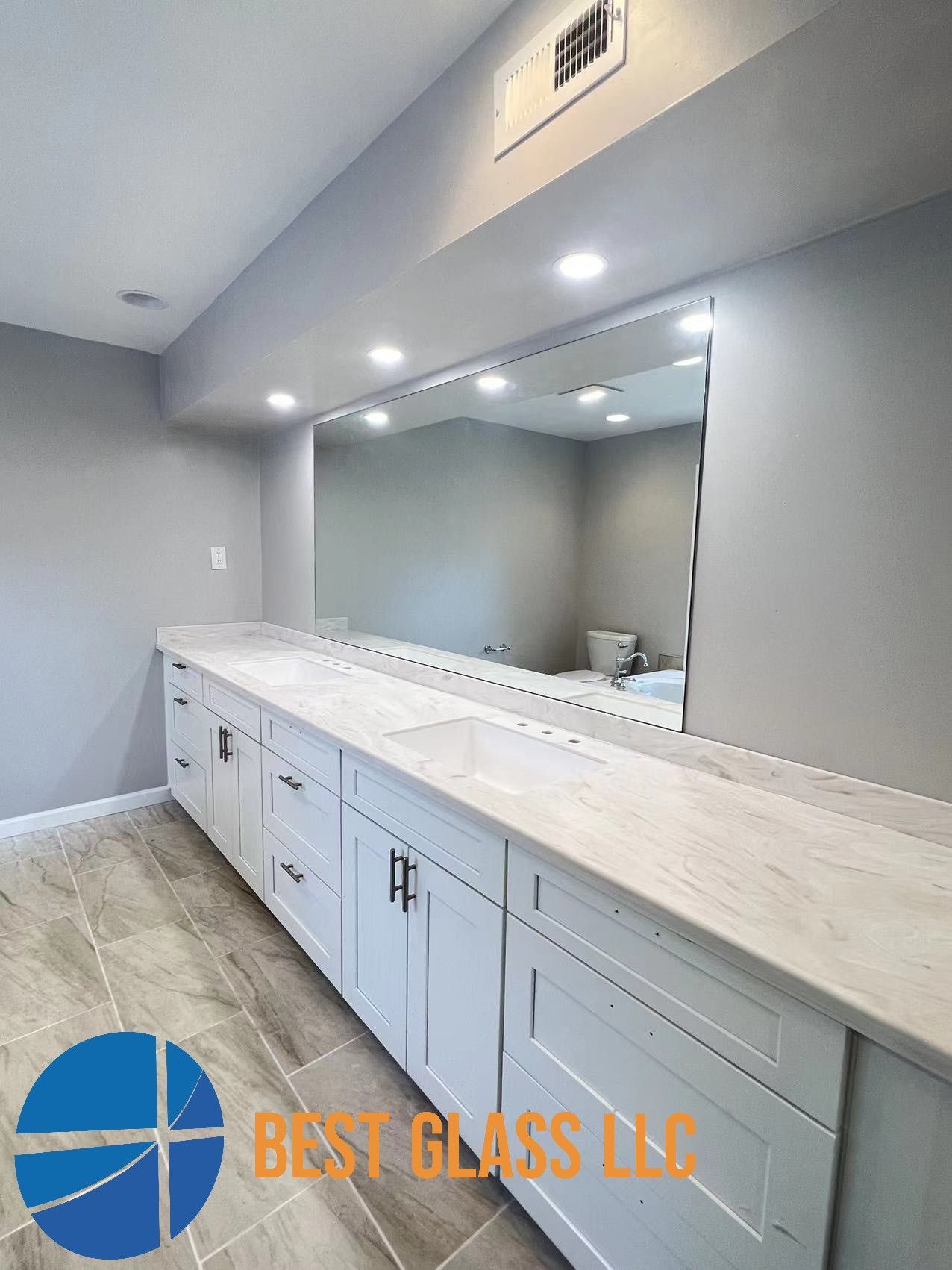 A bathroom with a large mirror and white cabinets.