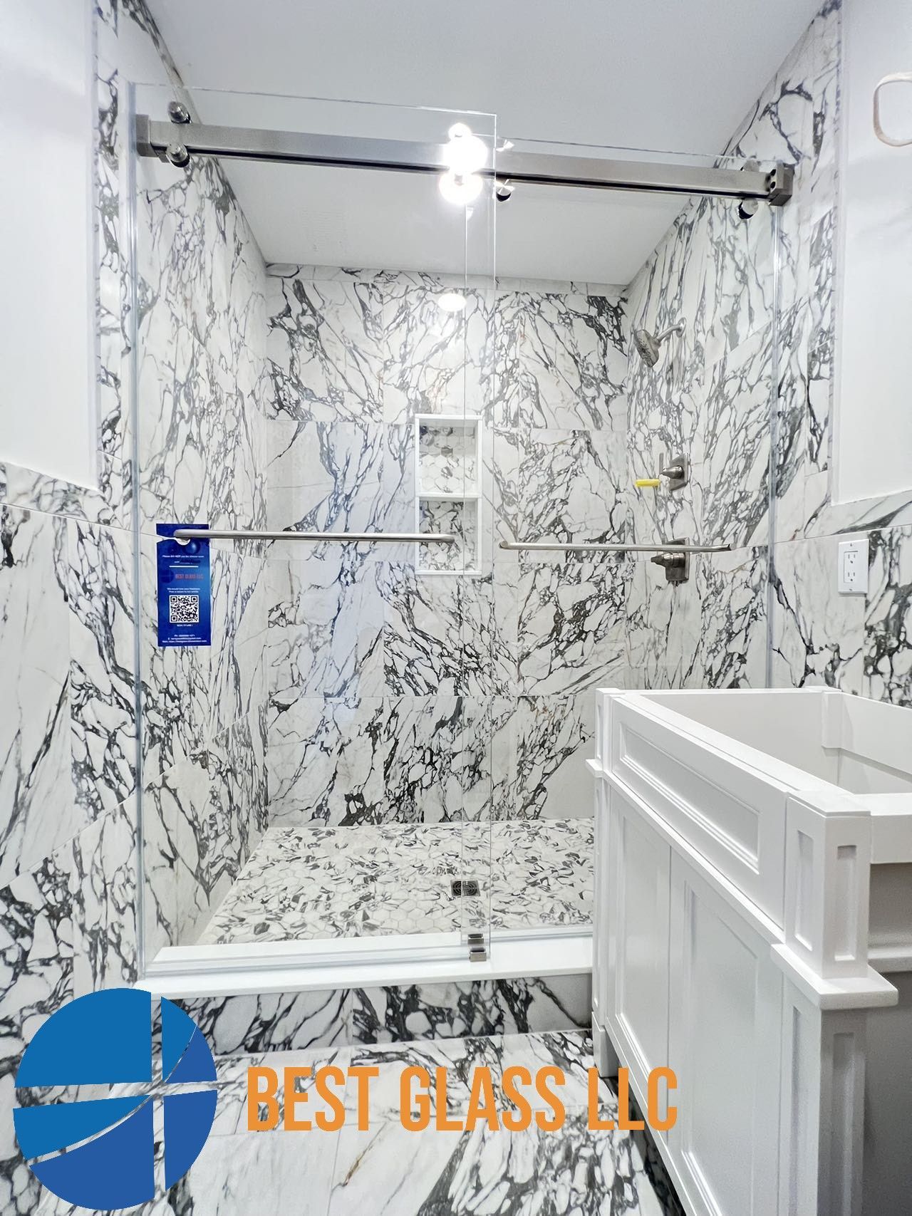 A bathroom with marble walls and a walk in shower.