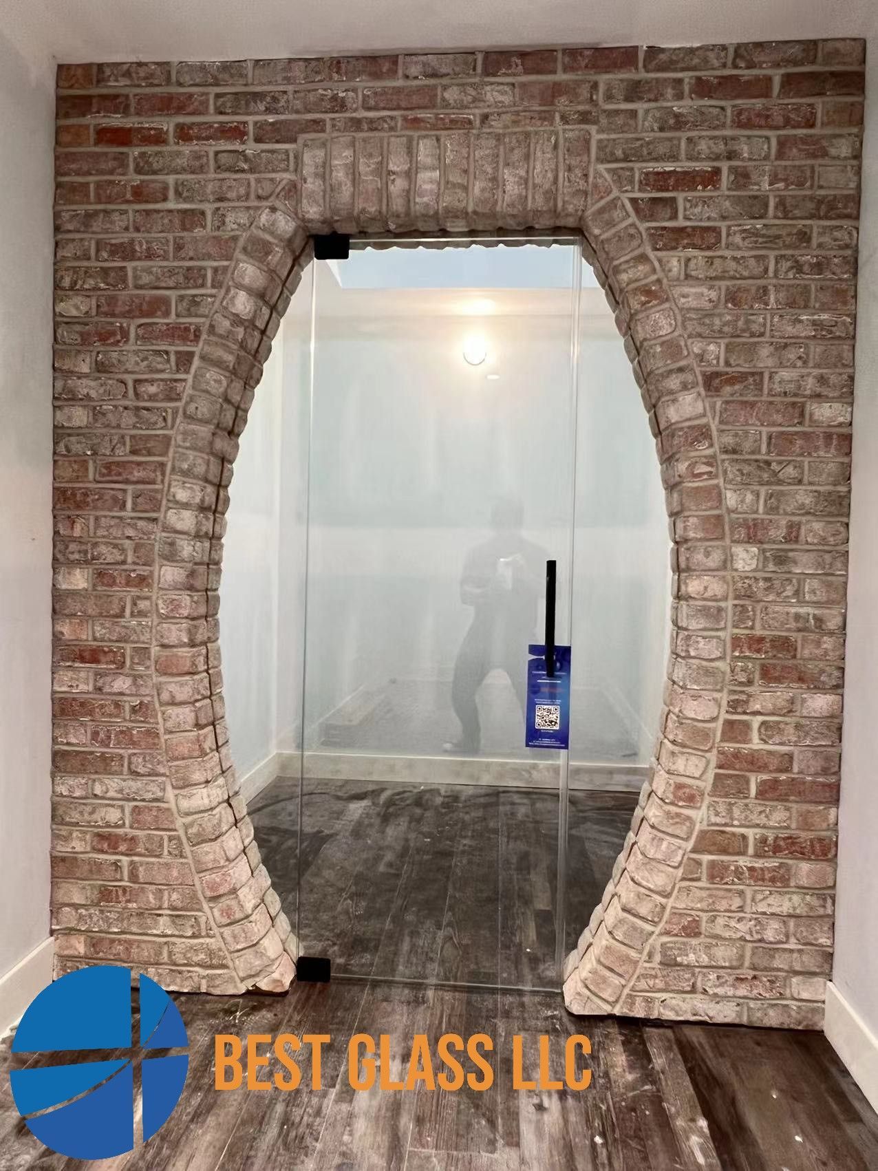 A brick wall with a glass door in the middle of it.