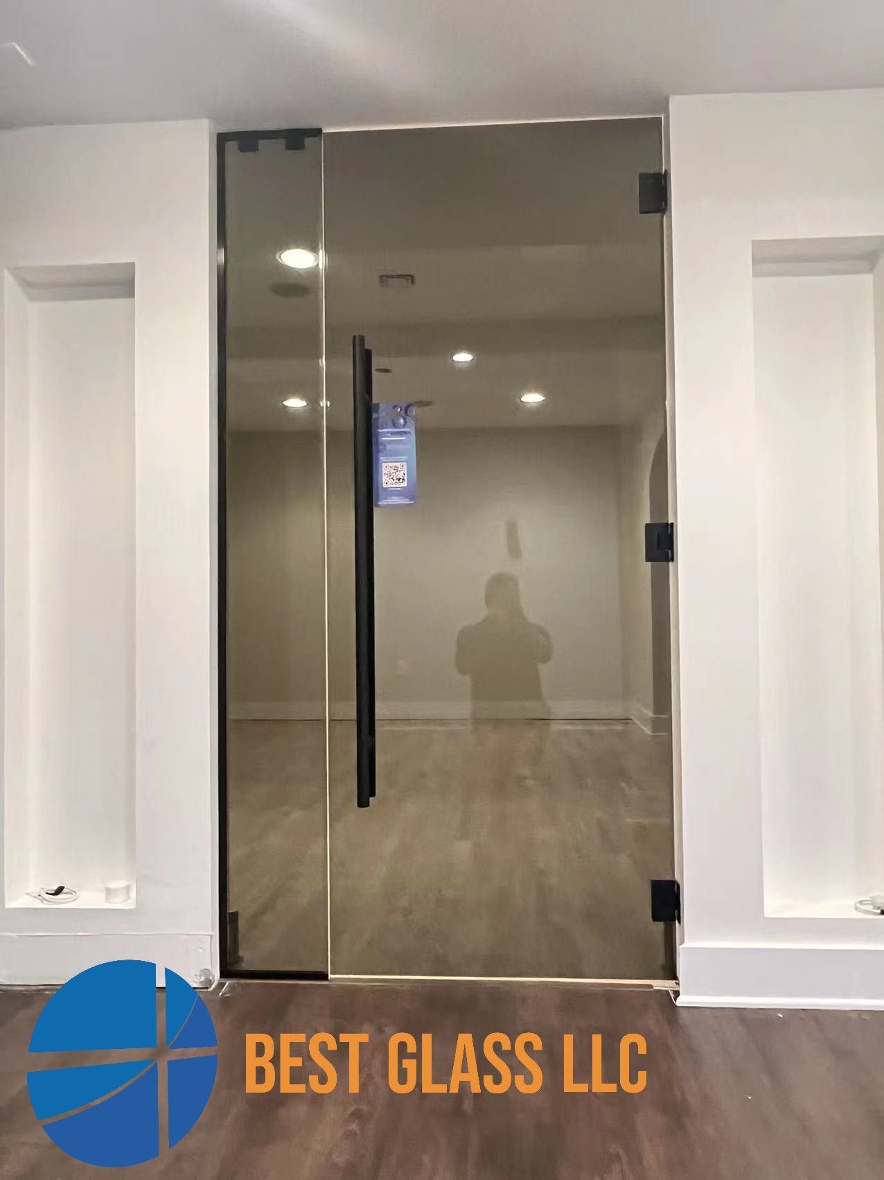A glass door with a black handle is in a room.