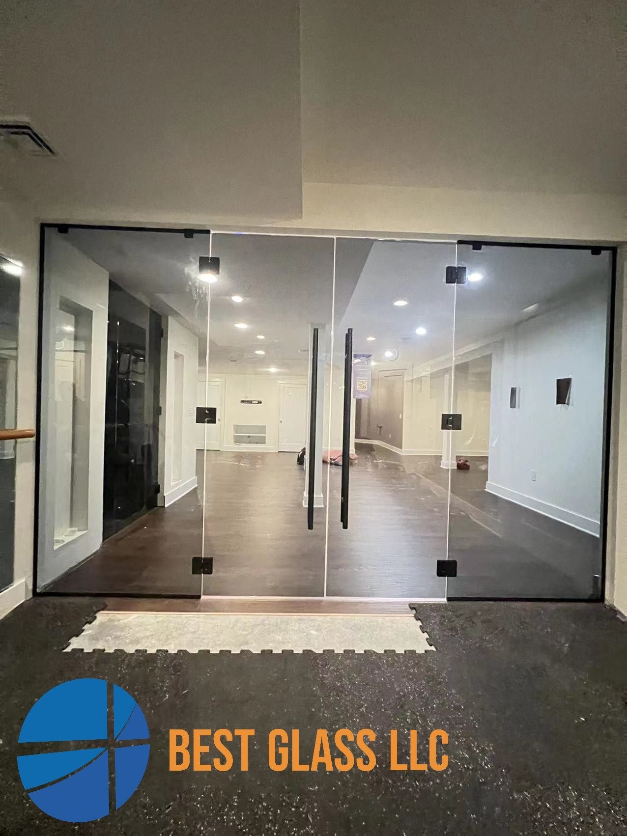 A room with a lot of glass doors and a logo for best glass llc.