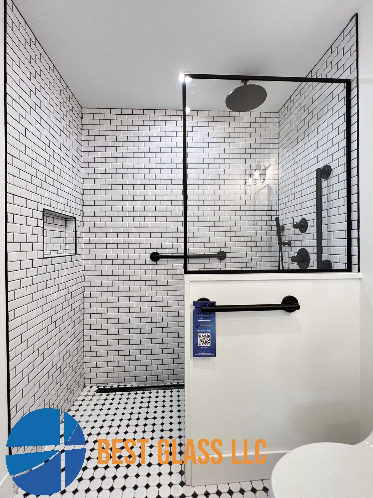 A bathroom with black and white tiles and a walk in shower
