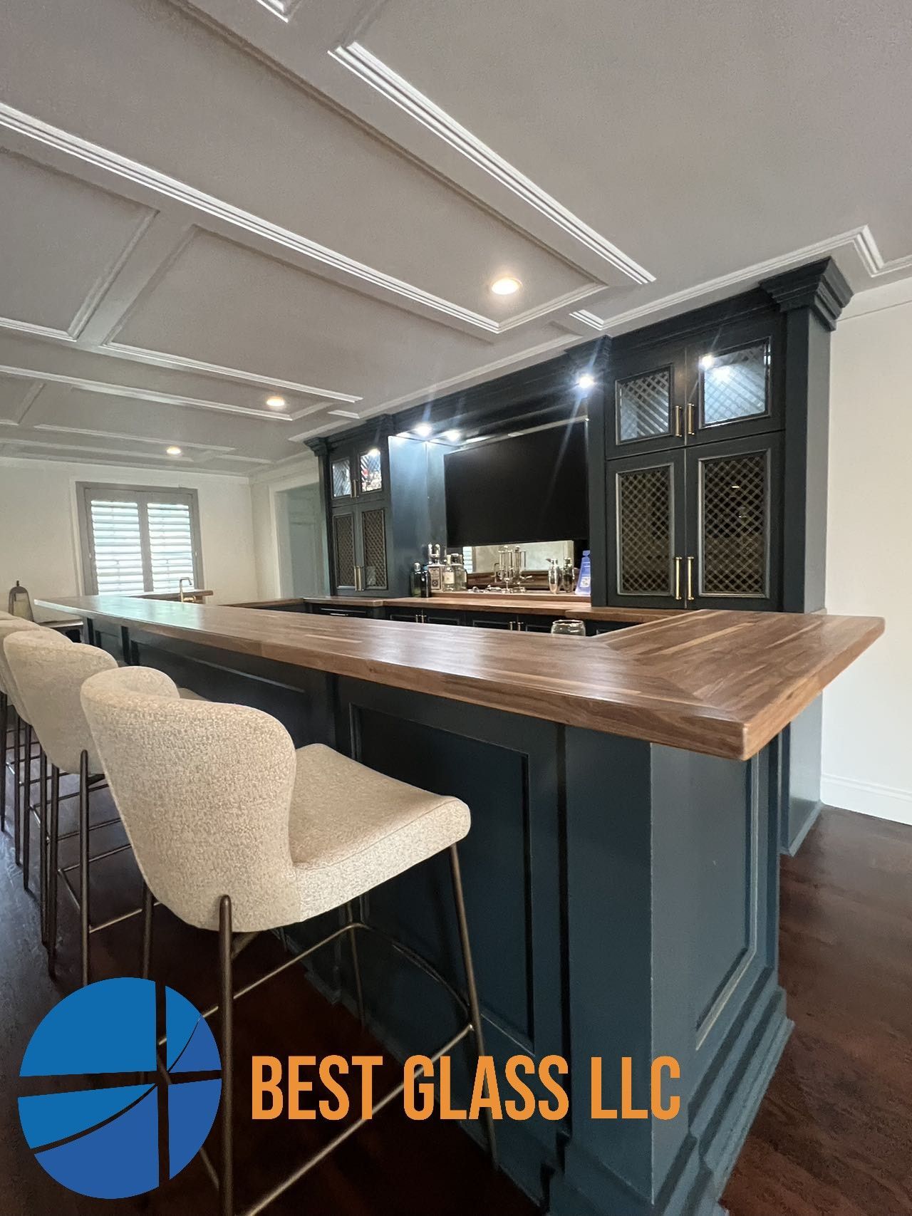 A kitchen with a bar and chairs and a logo for best glass llc.