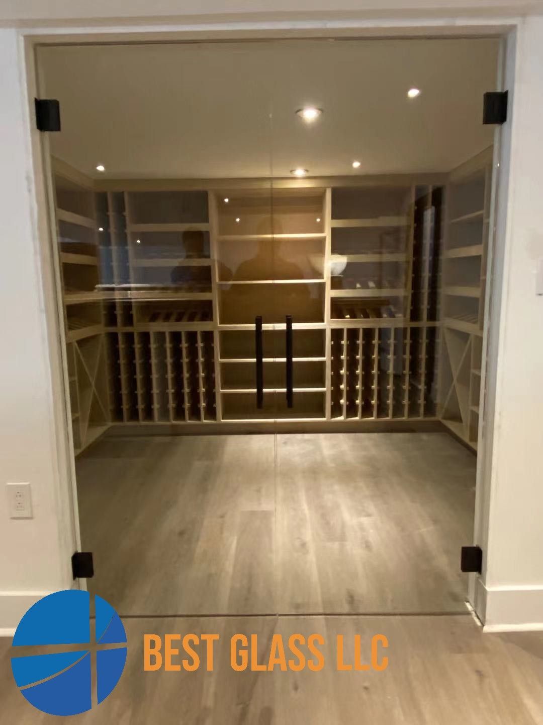 A wine cellar with a glass door and a sign that says best glass llc