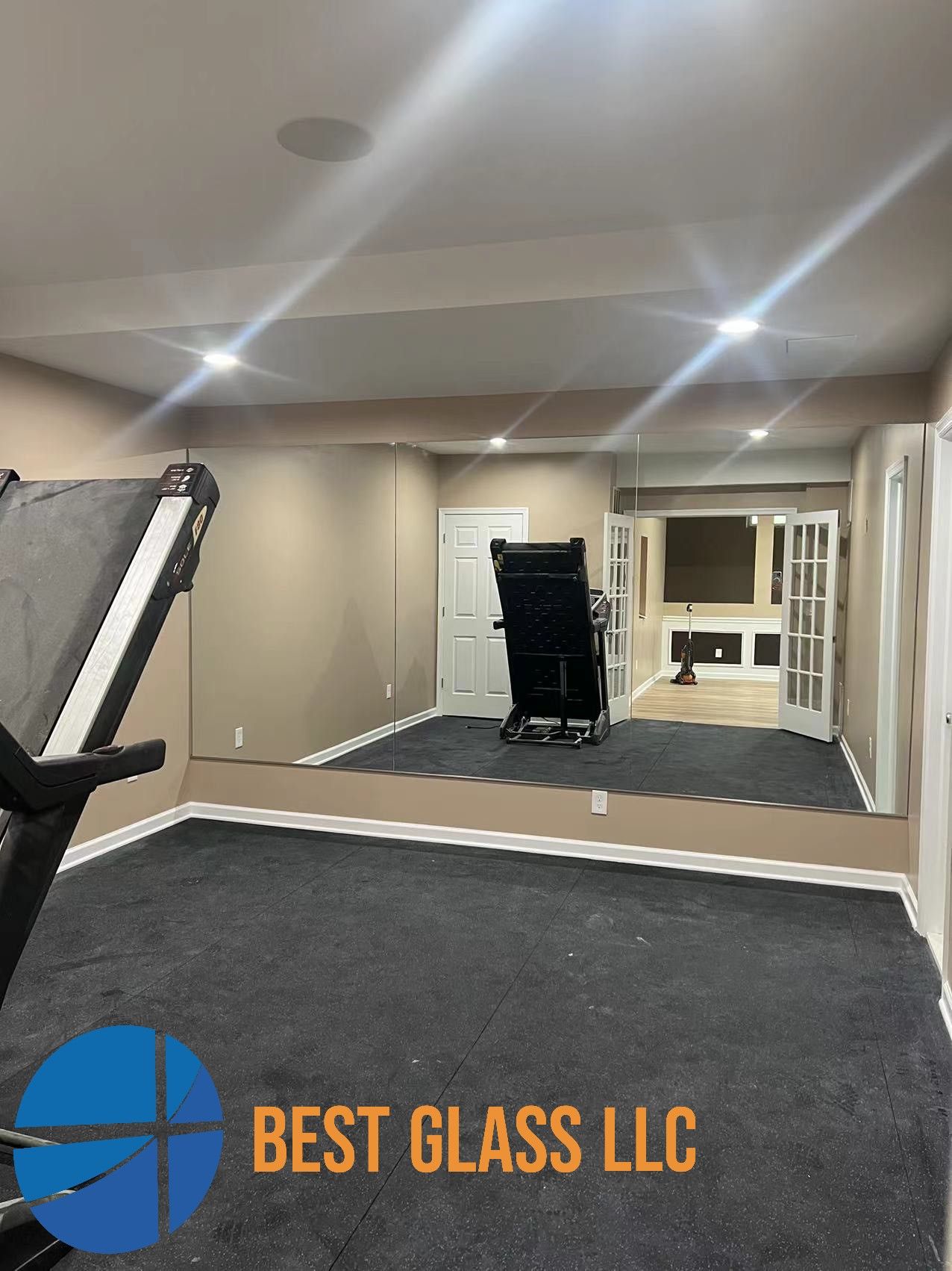 A room with a treadmill and a large mirror on the wall.