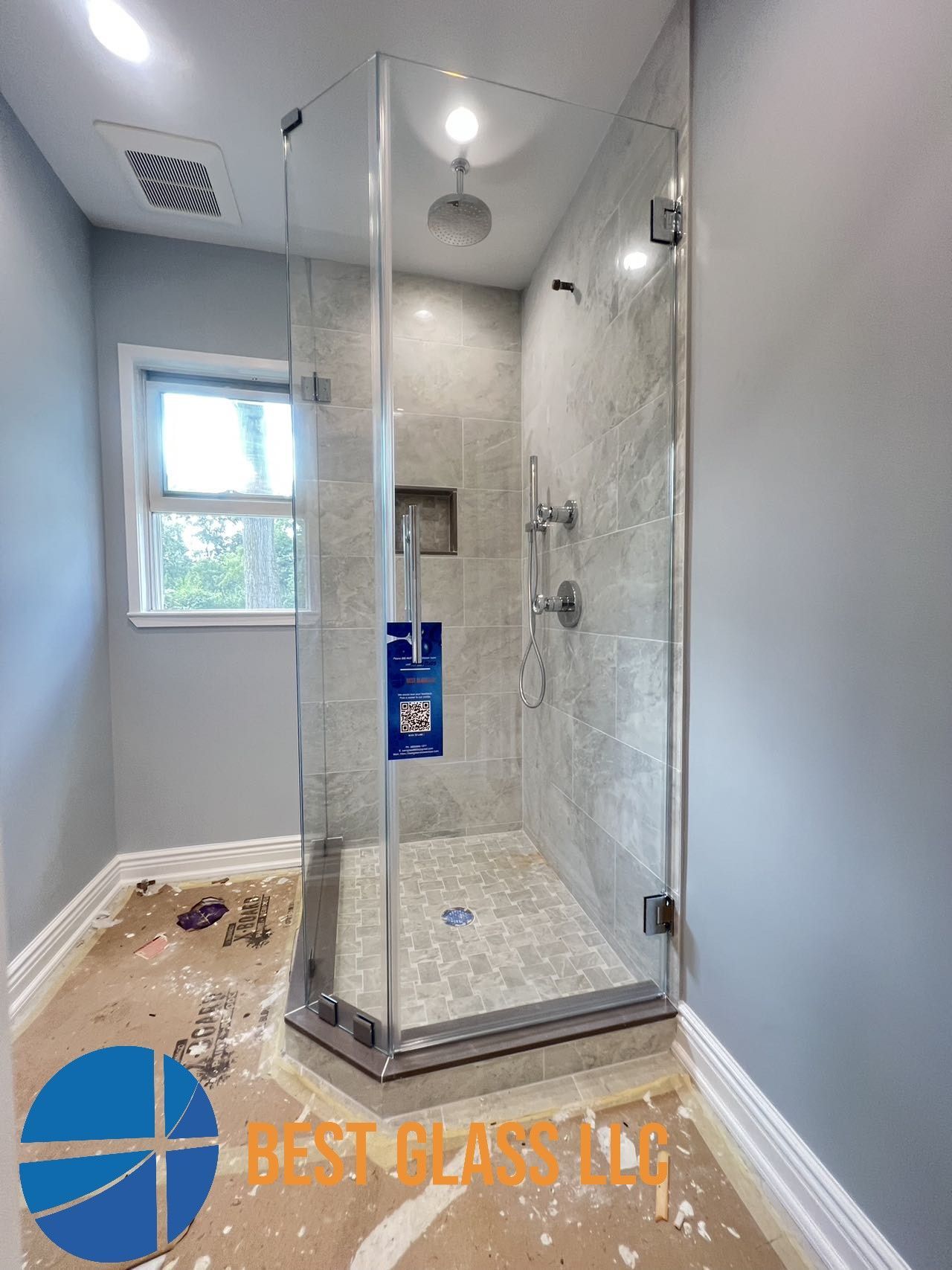 A bathroom with a shower stall and a window.