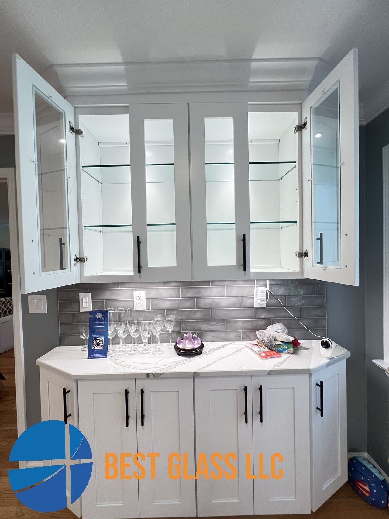 A kitchen with white cabinets and glass doors.