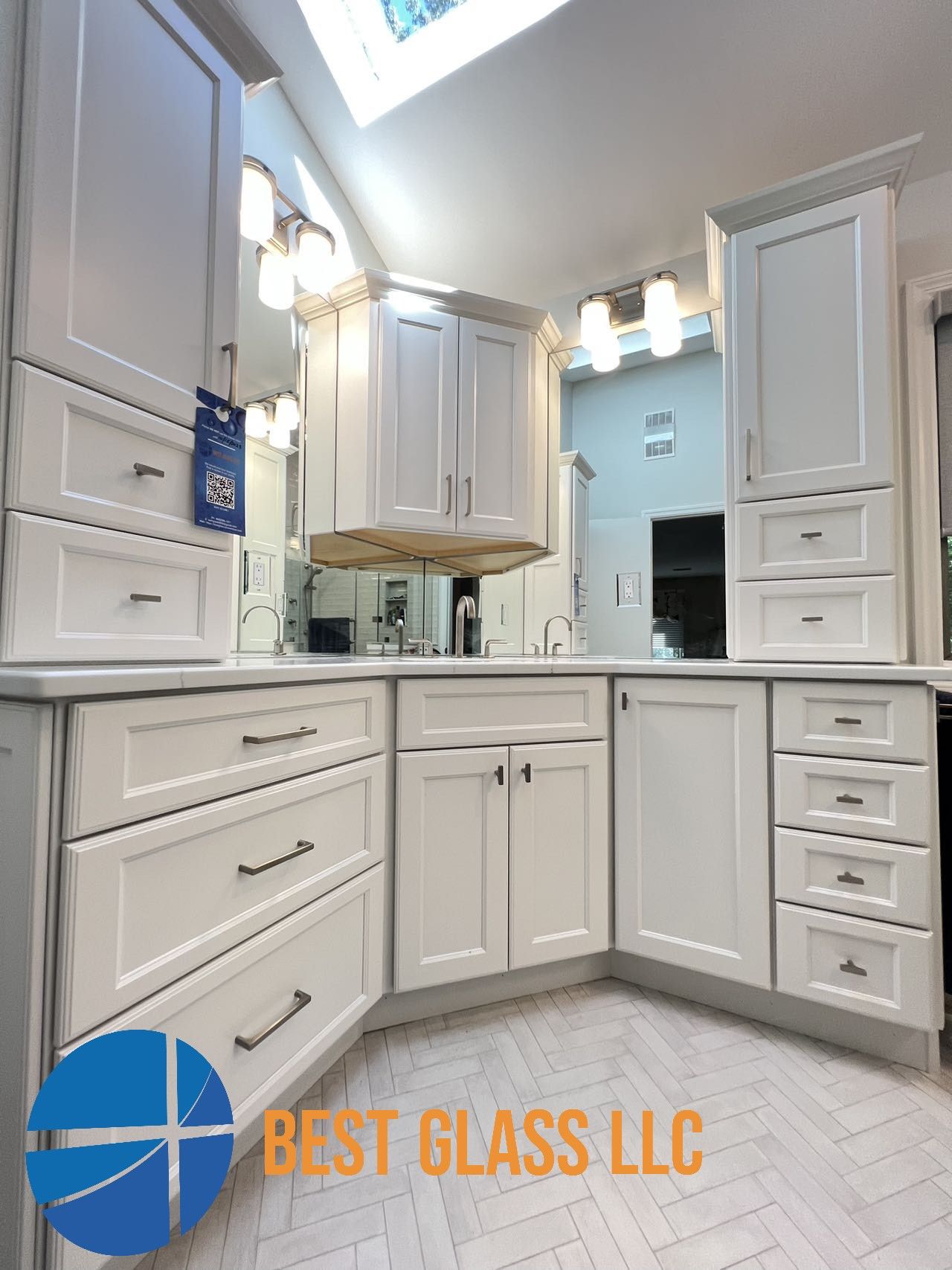 A bathroom with white cabinets and drawers and a logo for best glass llc