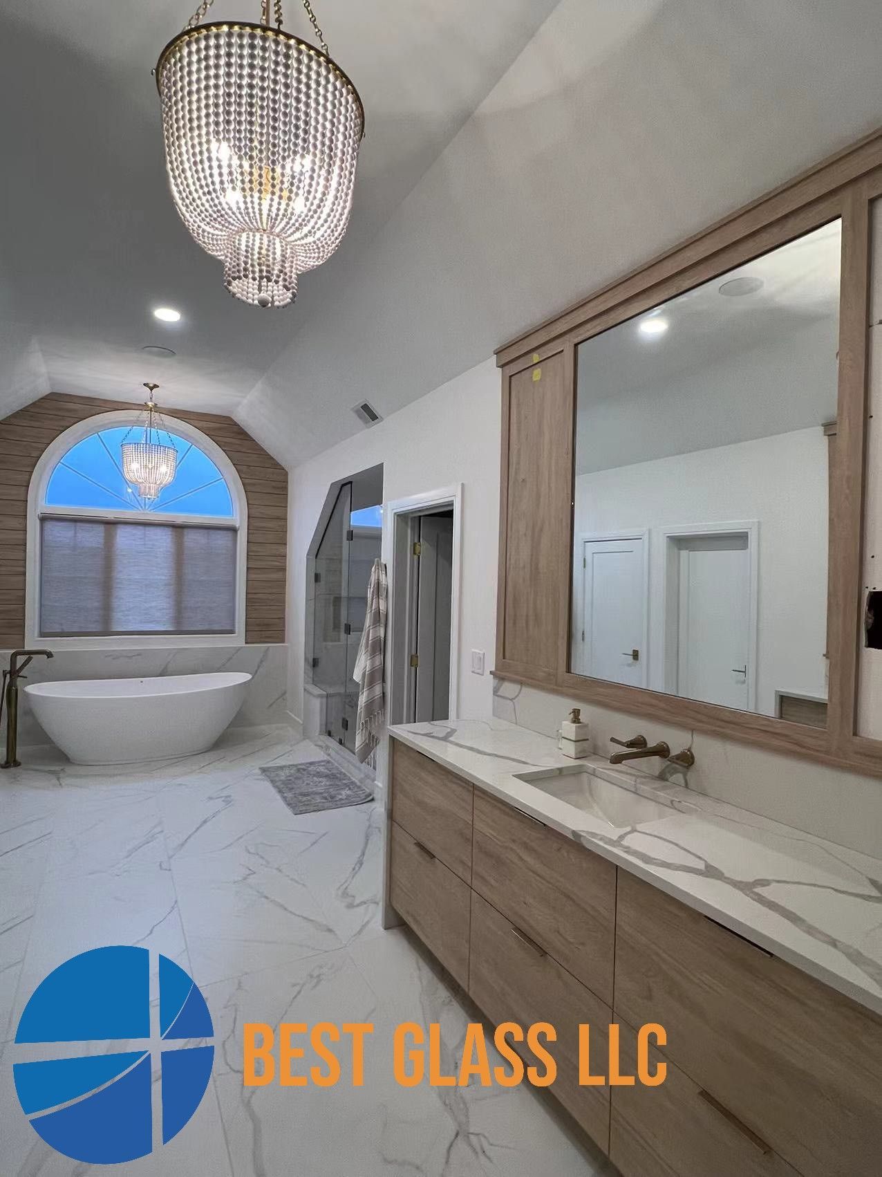 A bathroom with a bathtub , sink , mirror and chandelier.