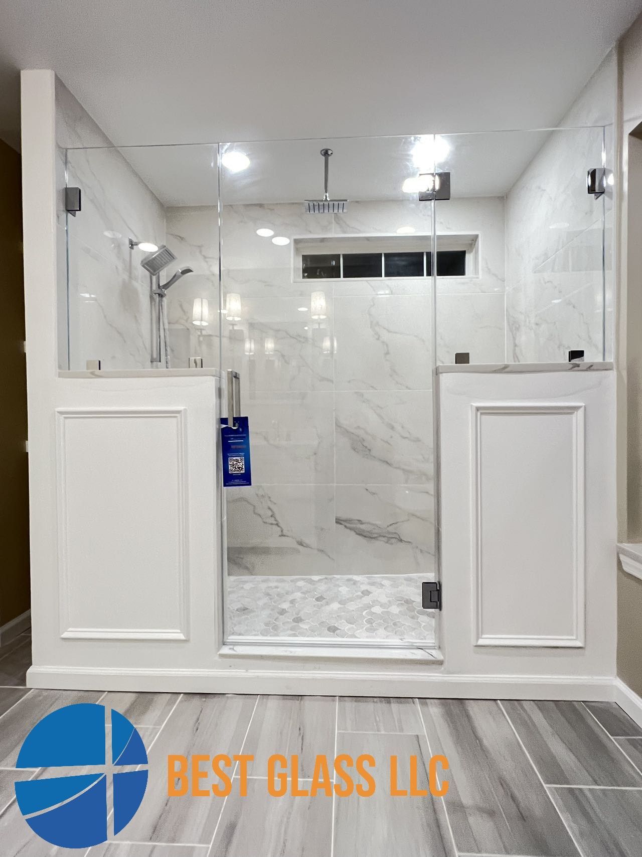 A bathroom with a walk in shower and a sign that says best glass llc