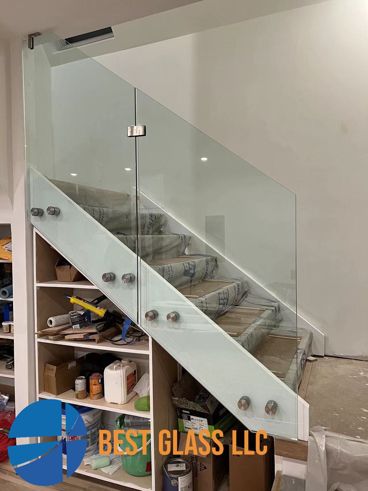 A staircase with a glass railing and a shelf underneath it.