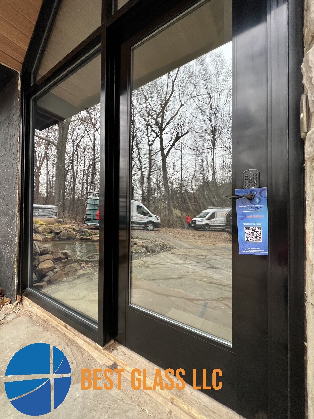 A black door with a reflection of trees in it.