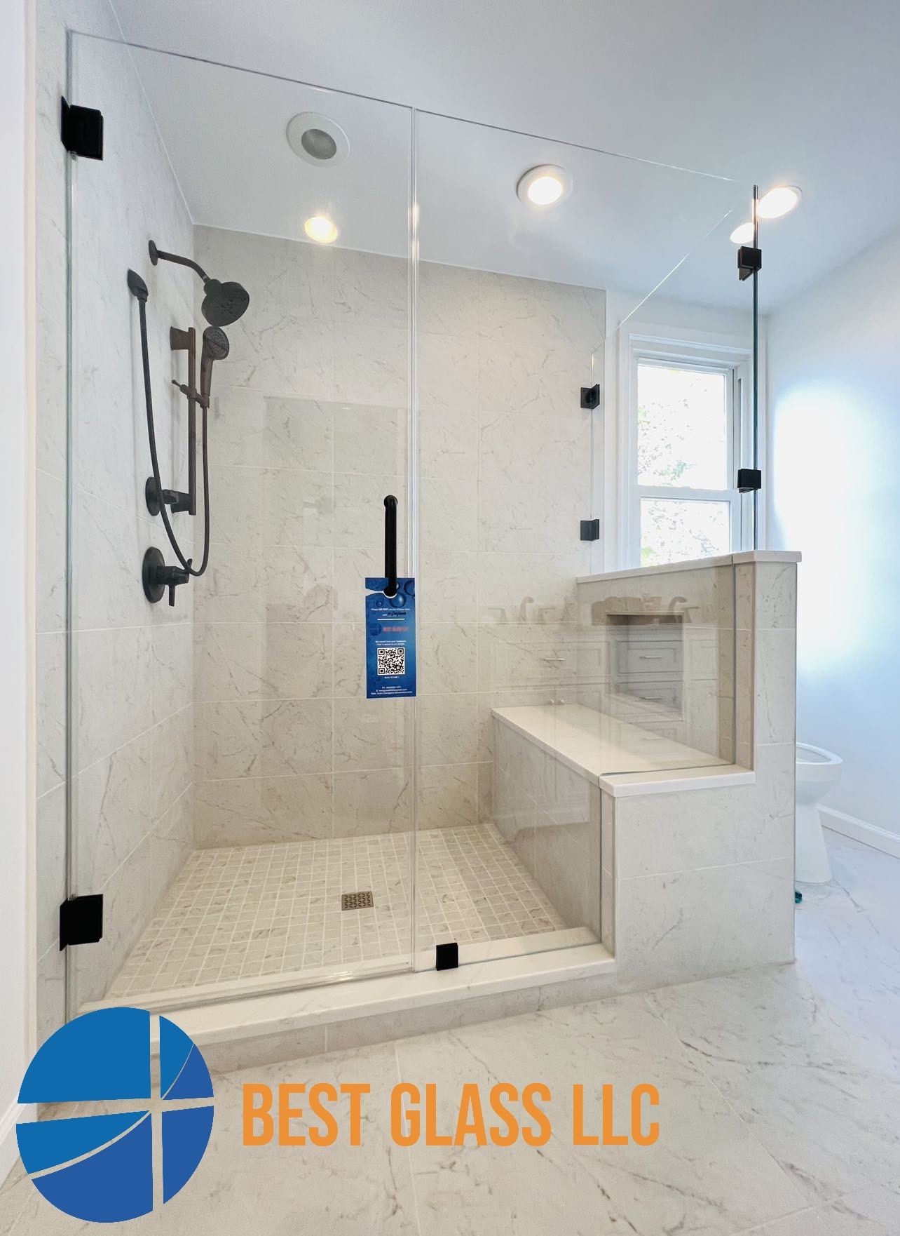 A bathroom with a walk in shower and a sign that says best glass llc