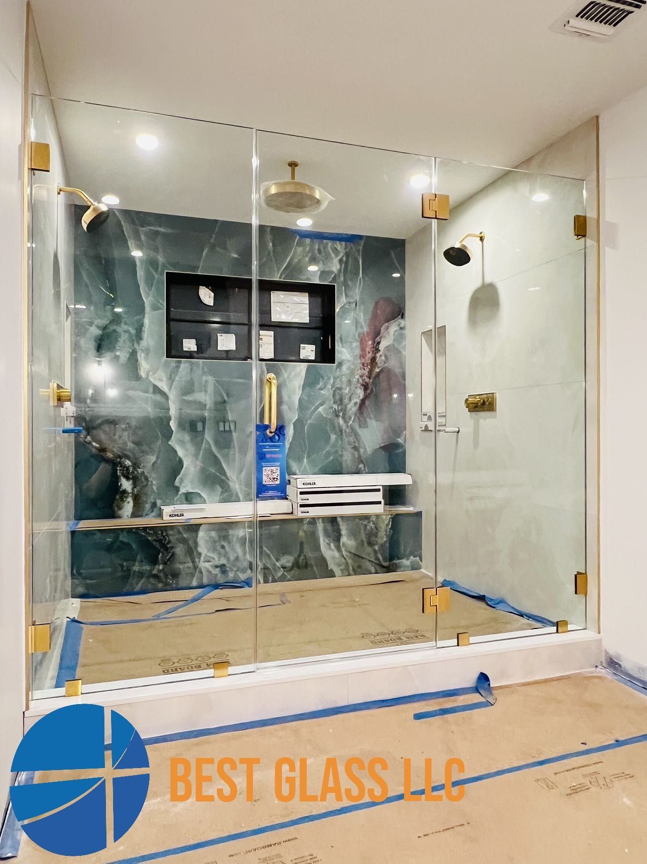 A bathroom with a glass shower door and a marble wall.
