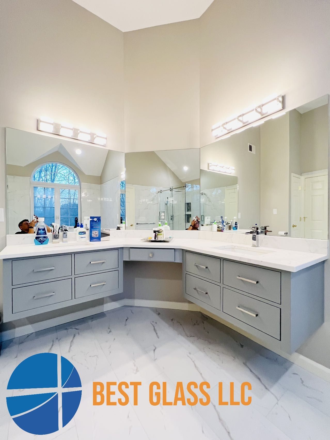 A bathroom with two sinks and a large mirror by best glass llc