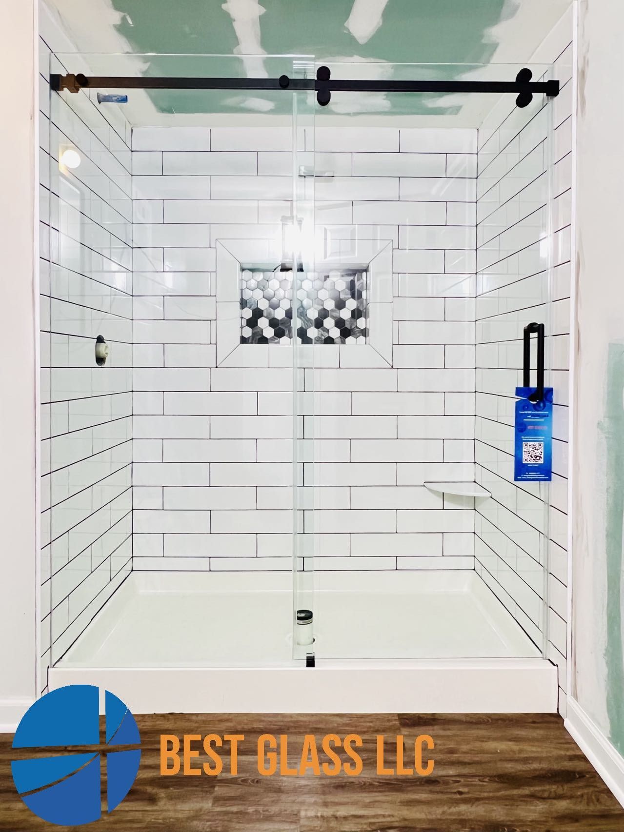 A bathroom with white tiles and a sliding glass shower door.