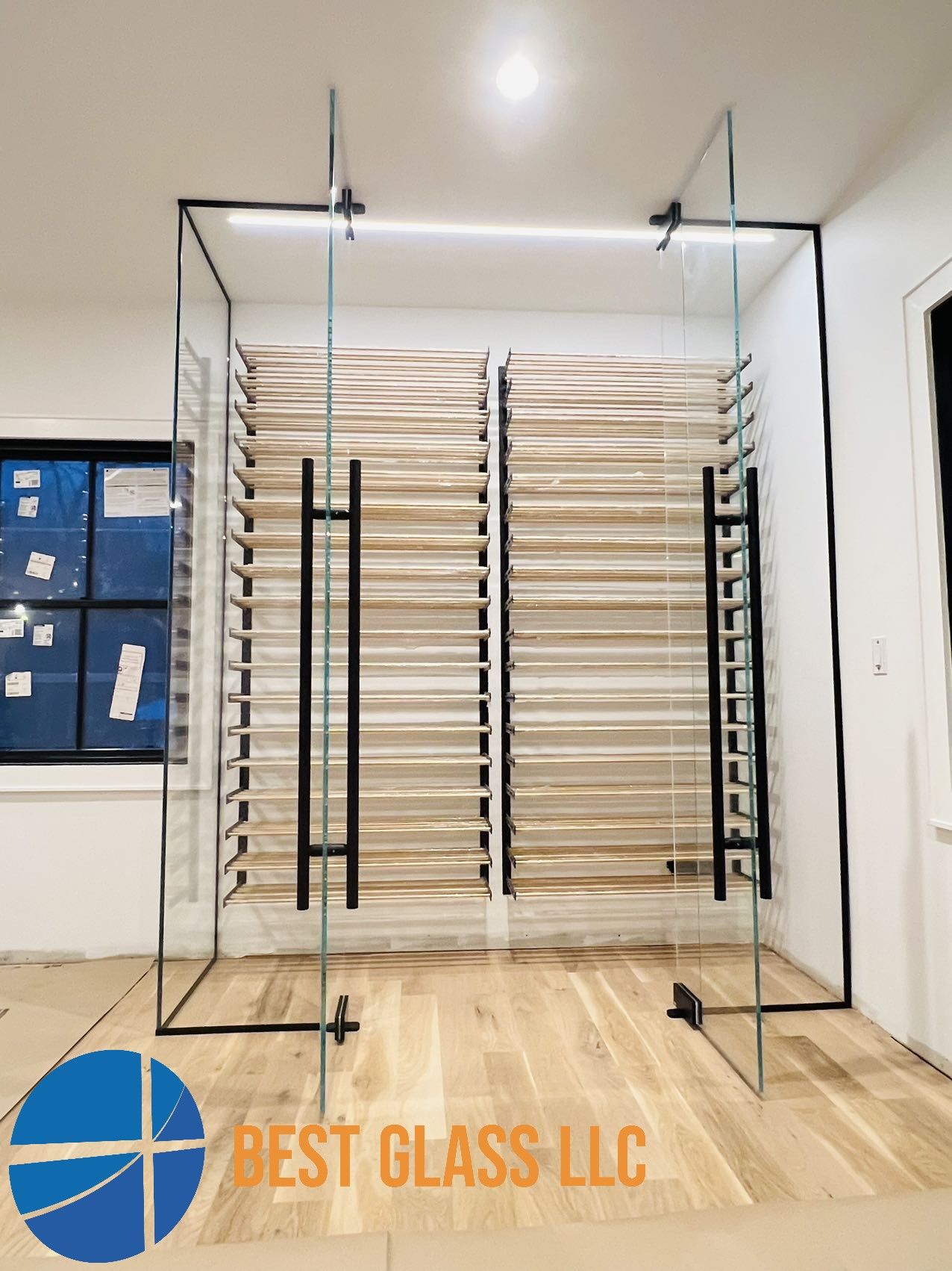 A room with a glass wall and a sign that says best glass llc