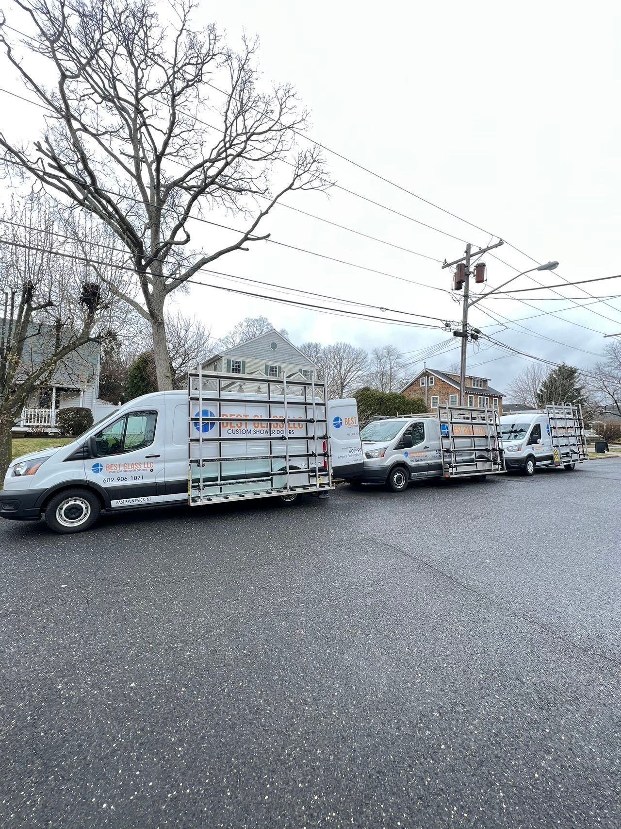 A row of white vans are parked on the side of the road.