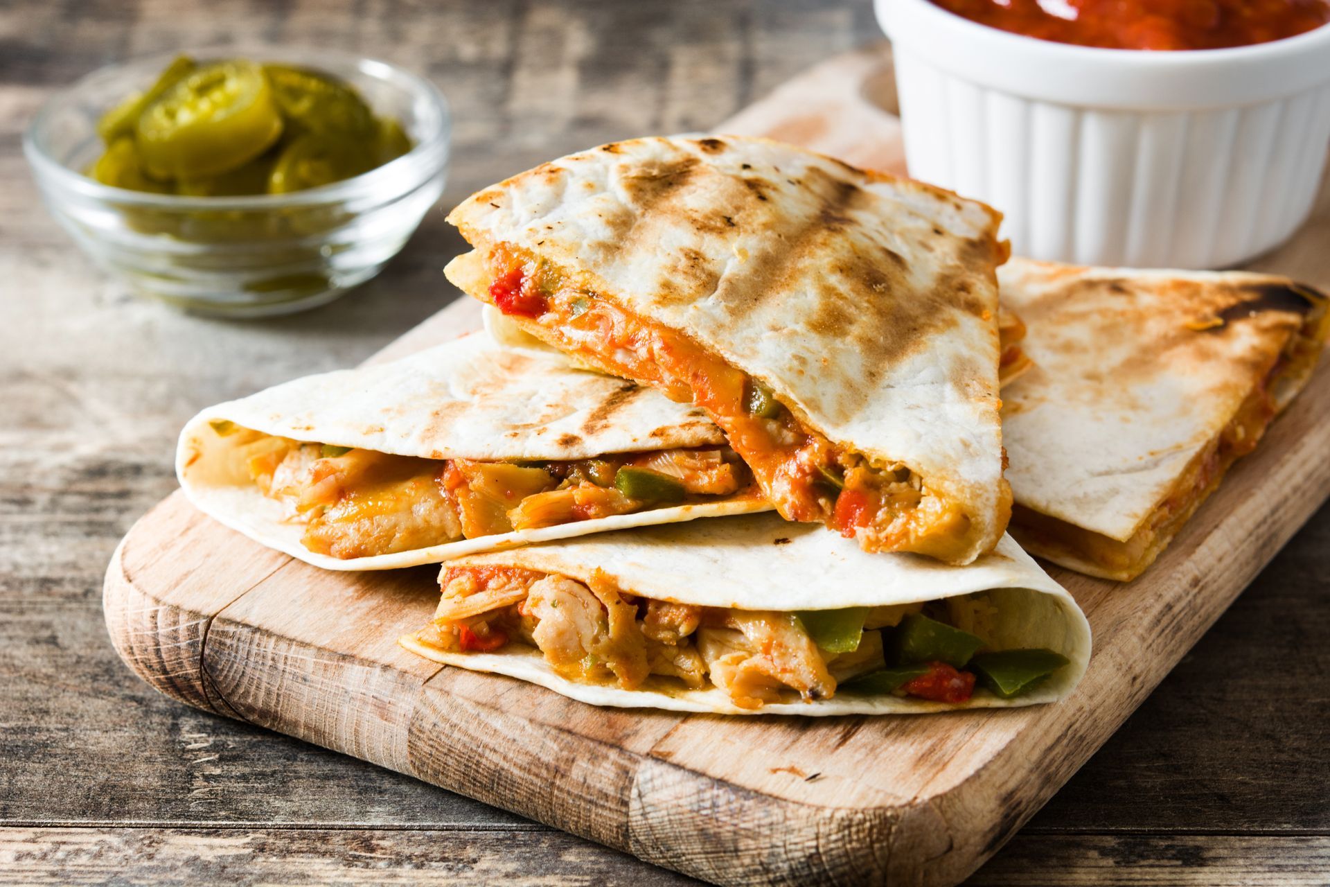A close up of a quesadilla on a wooden cutting board.