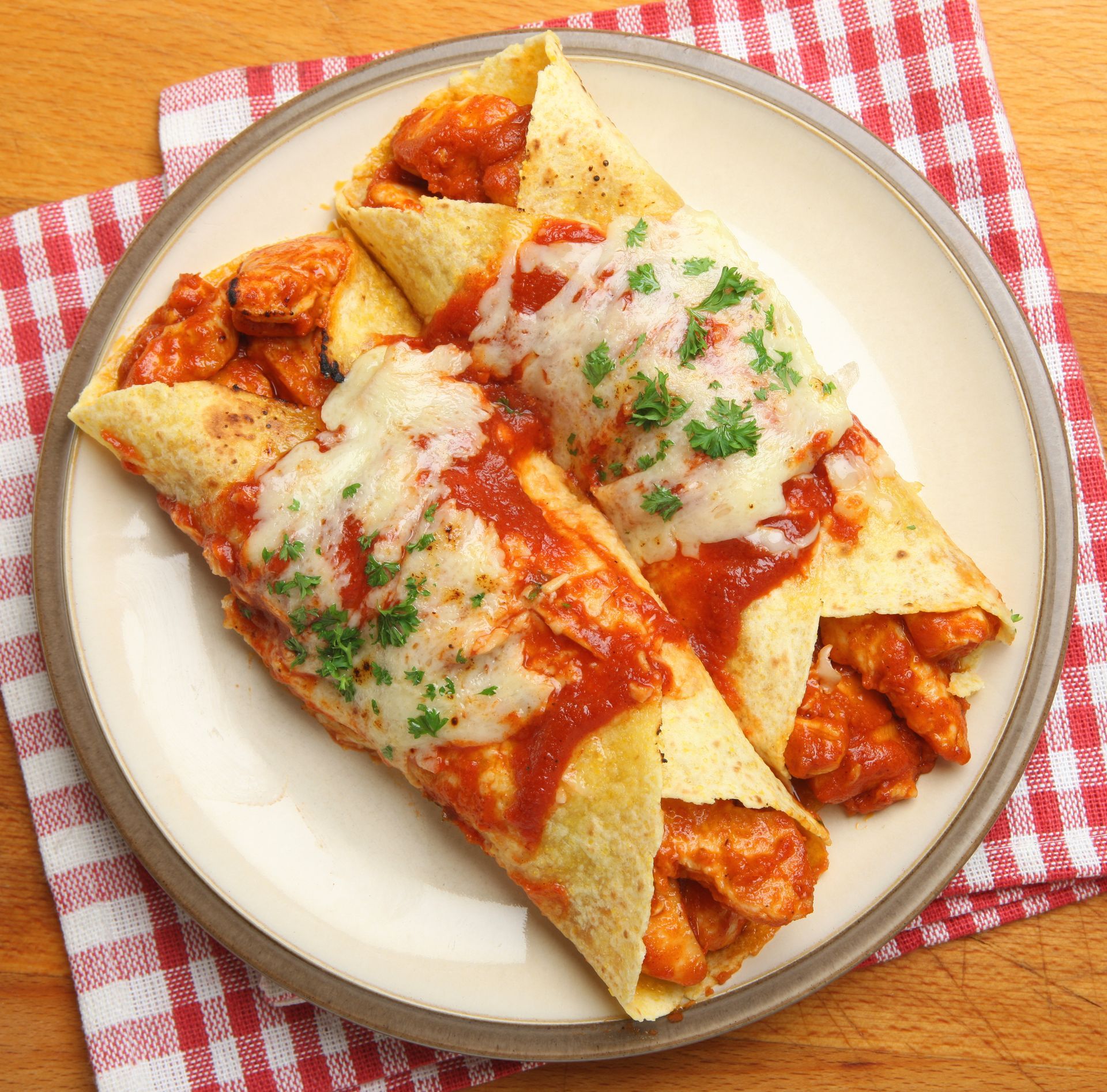 Two enchiladas on a plate with tomato sauce and cheese