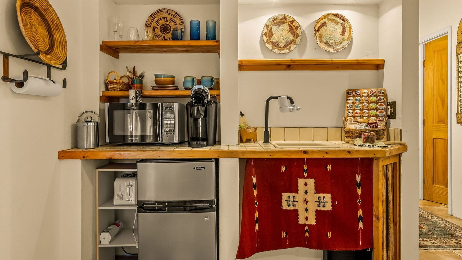 A small kitchen with a refrigerator , sink , microwave , and shelves.