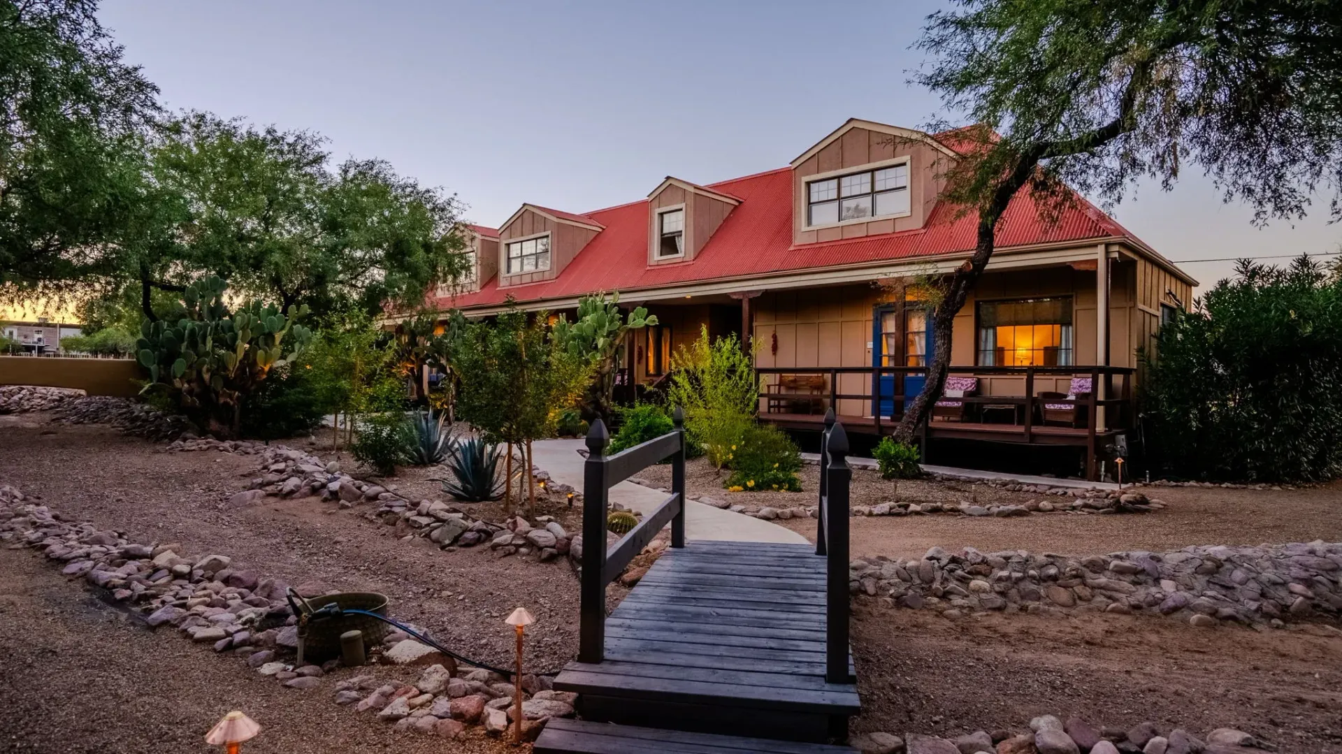 A house with a red roof and a wooden bridge leading to it