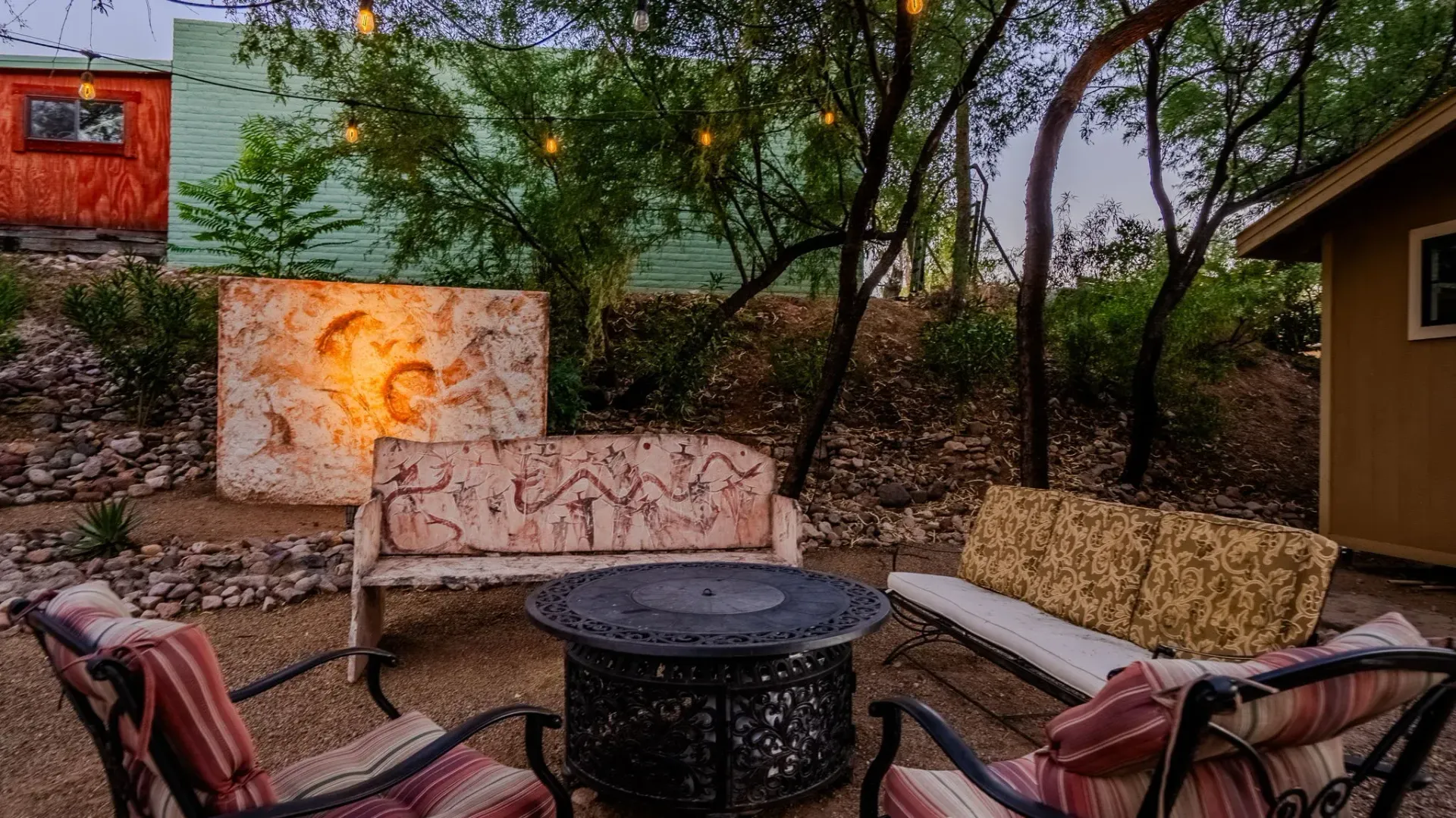 A group of chairs and a couch are sitting around a fire pit in a backyard.