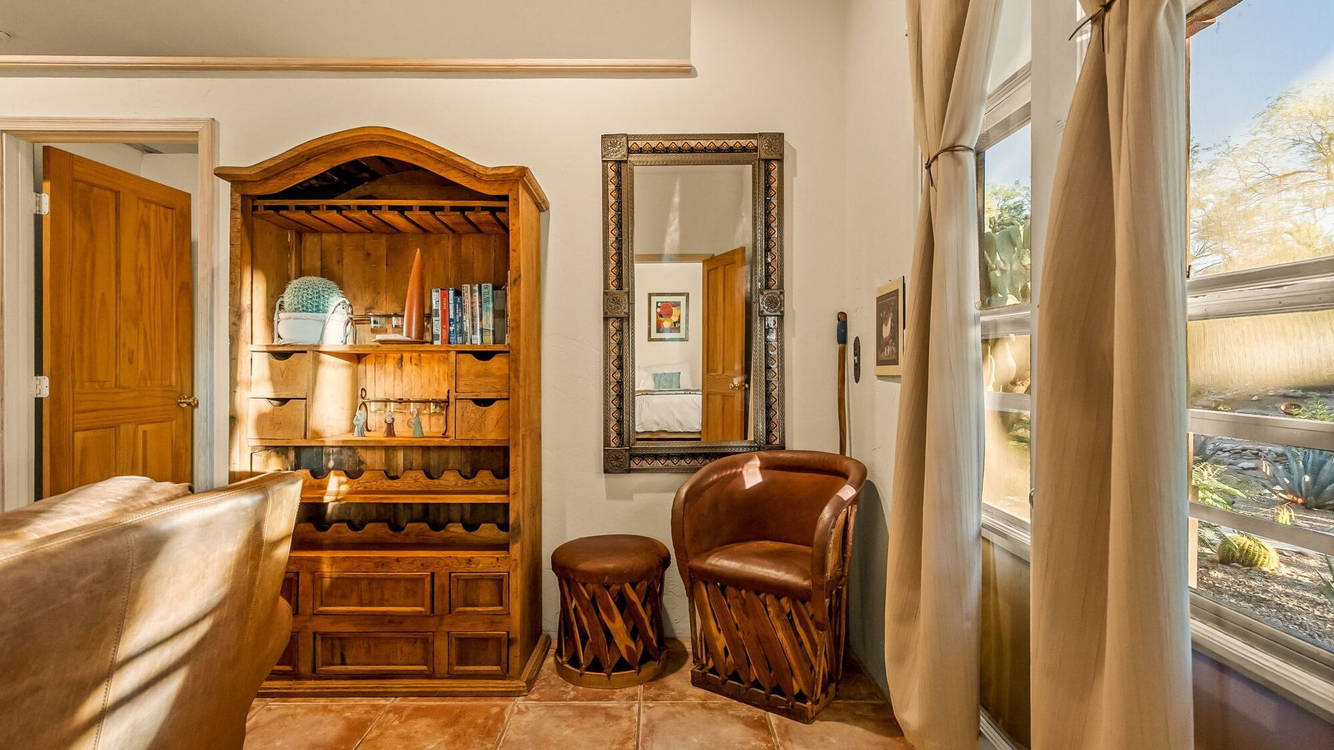 A living room with a couch , chairs , a wine rack and a mirror.