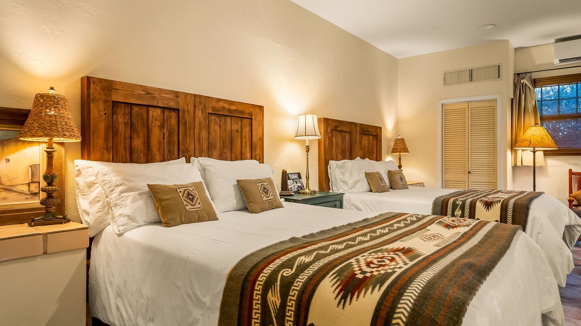 A hotel room with two beds and two lamps.