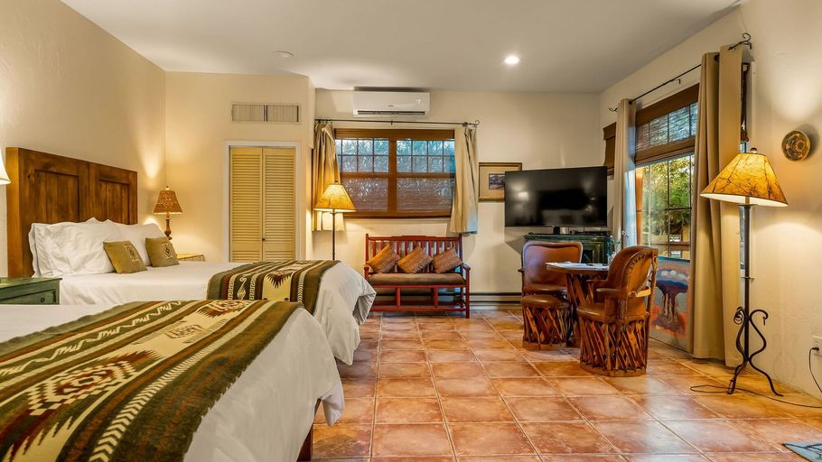 A hotel room with two beds , a couch , and a flat screen tv.