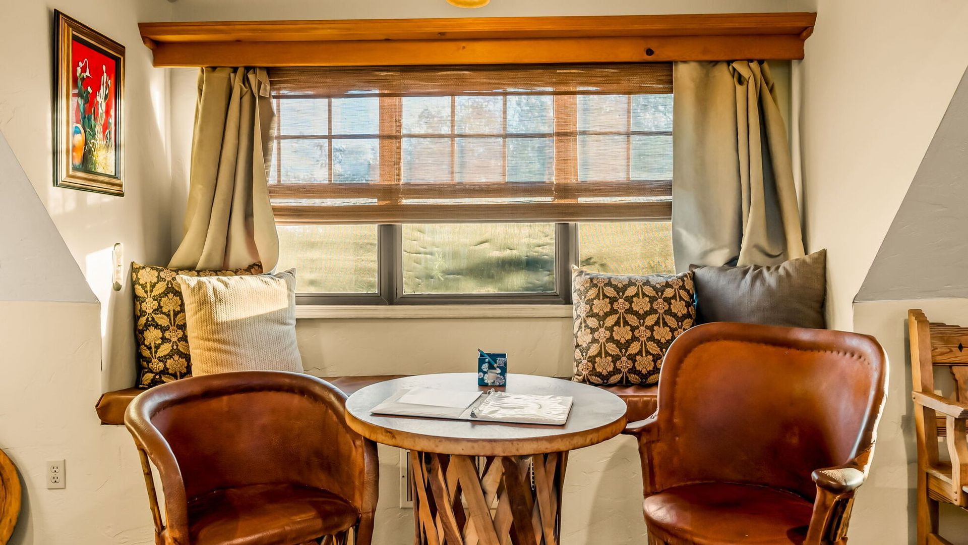 A living room with two chairs and a table in front of a window.