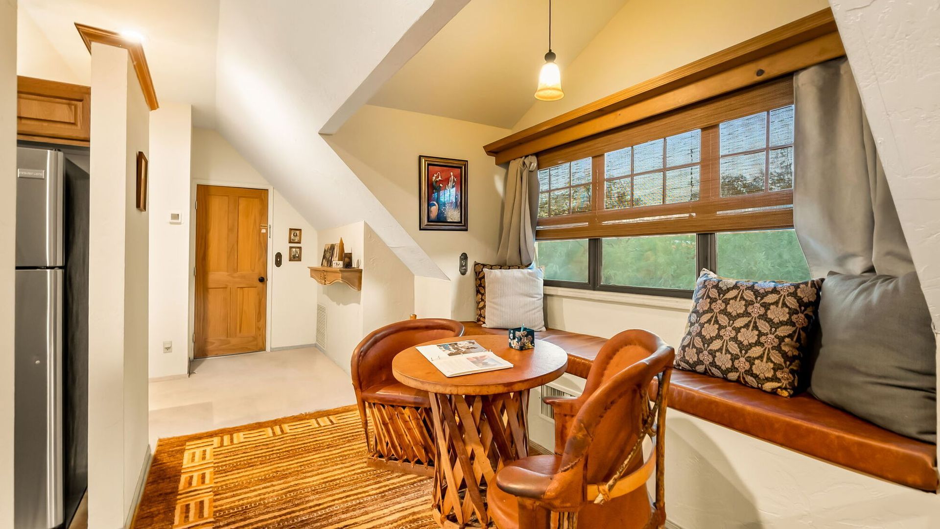 A living room with a table and chairs in front of a window.