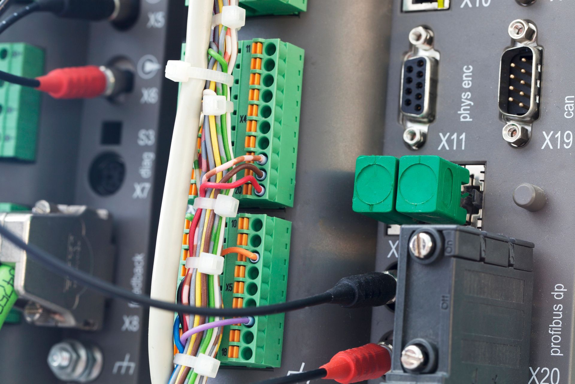 Primo piano del pannello di controllo industriale con morsettiere, fili e connettori verdi, che mettono in mostra i componenti elettronici.