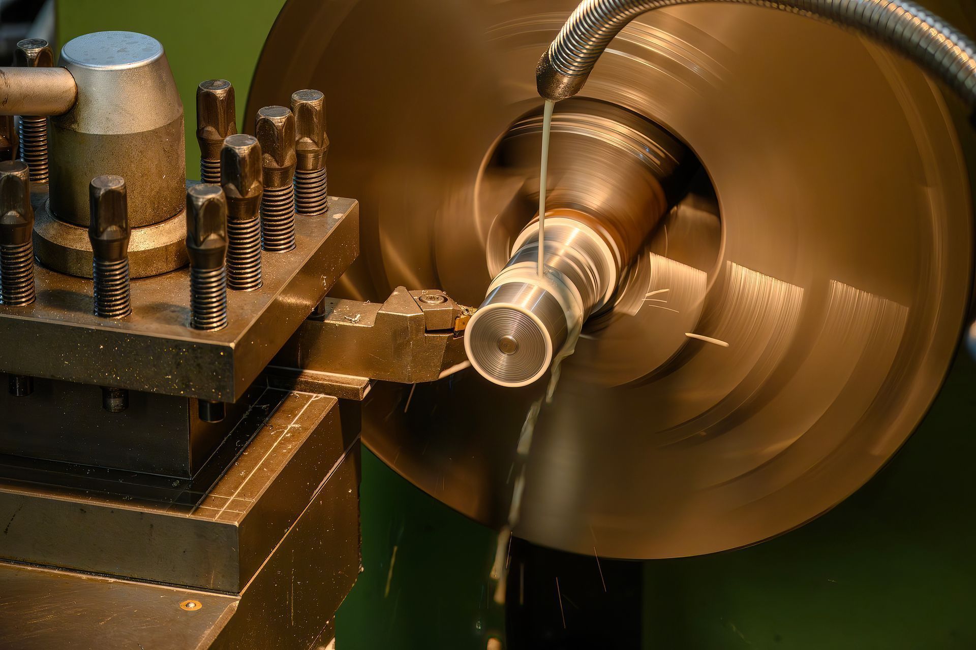 Tornio che taglia un cilindro metallico, lubrificante che scorre.