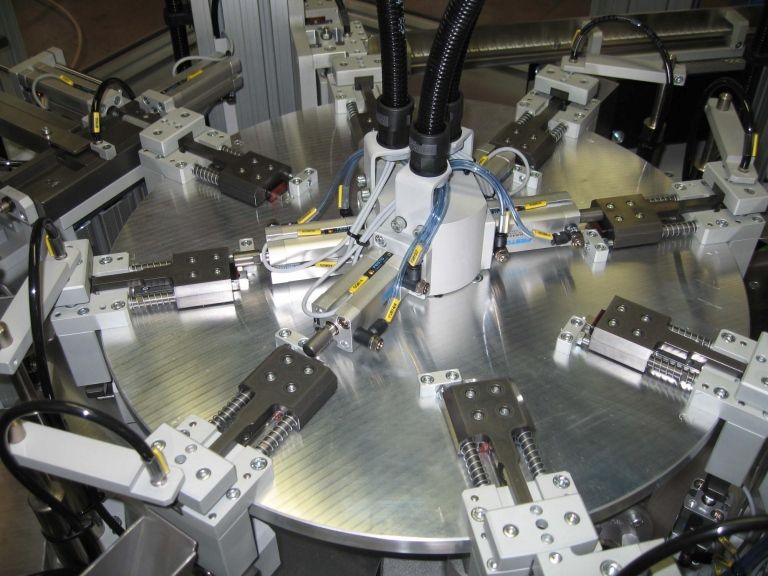 Giradischi industriale automatizzato con bracci robotici, argento metallizzato, rotante.