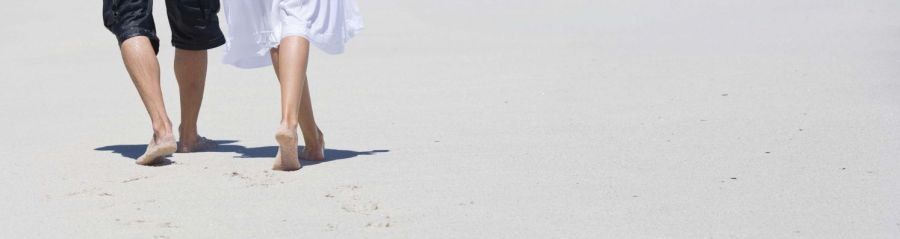 Couple walking barefoot on beach