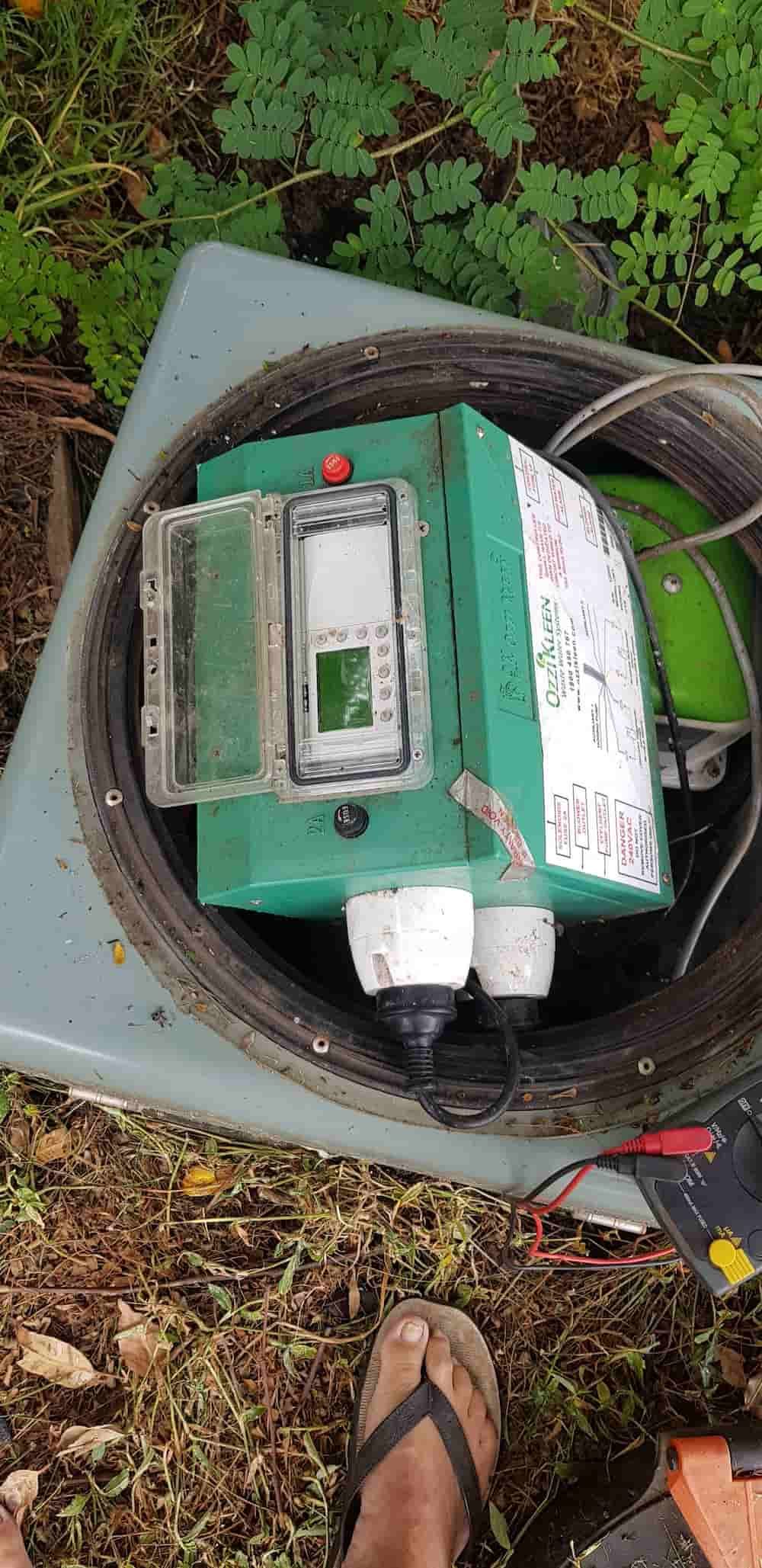 A Person Is Standing Next To A Green Box In A Hole In The Ground — Northern Rivers and Cape Hawke Septics in Forster, NSW